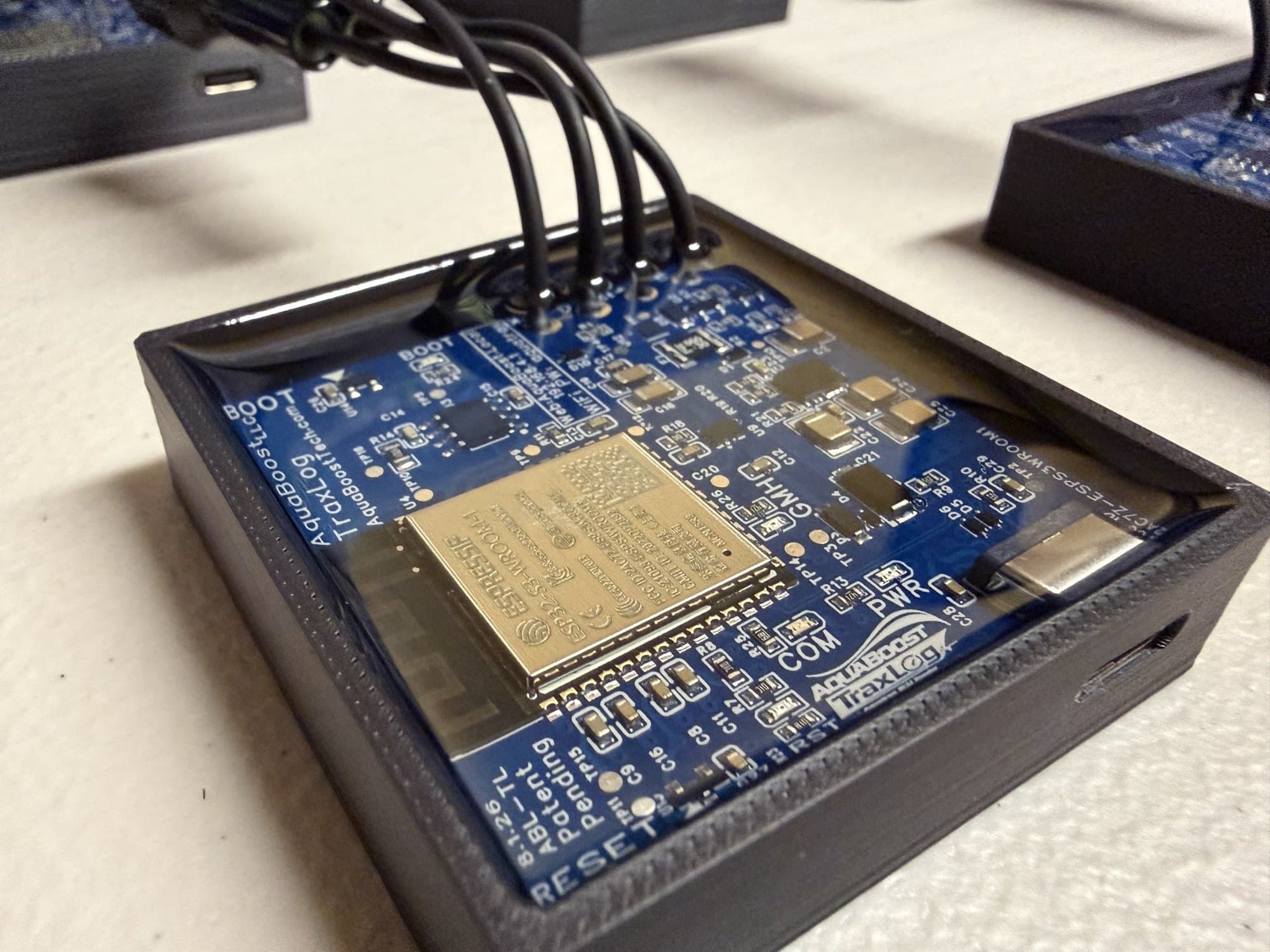 Close-up of an AquaBoost TraxLog module — circuit board with the ESP32-S3 and the four-wire DLC harness